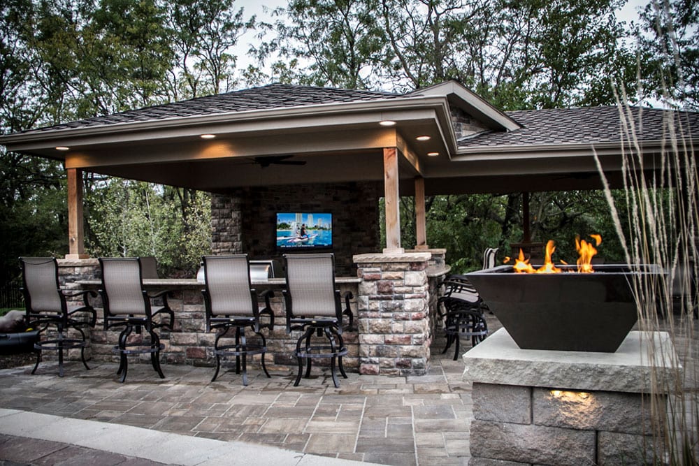 outdoor covered entertainment area with fire feature next to pool